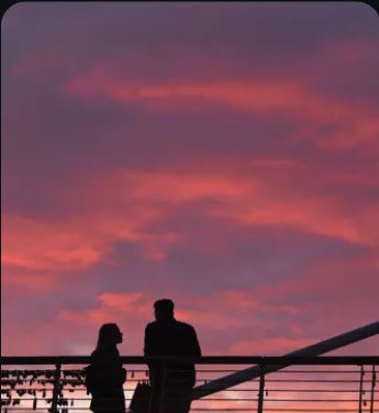 Two people silhouetted against a pink sunset
